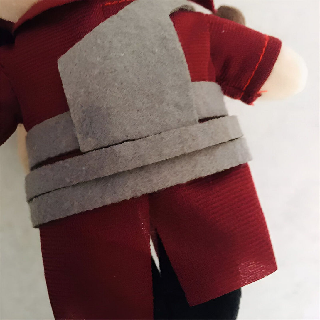 Une peluche de Naruto portant un vêtement rouge avec une ceinture grise.