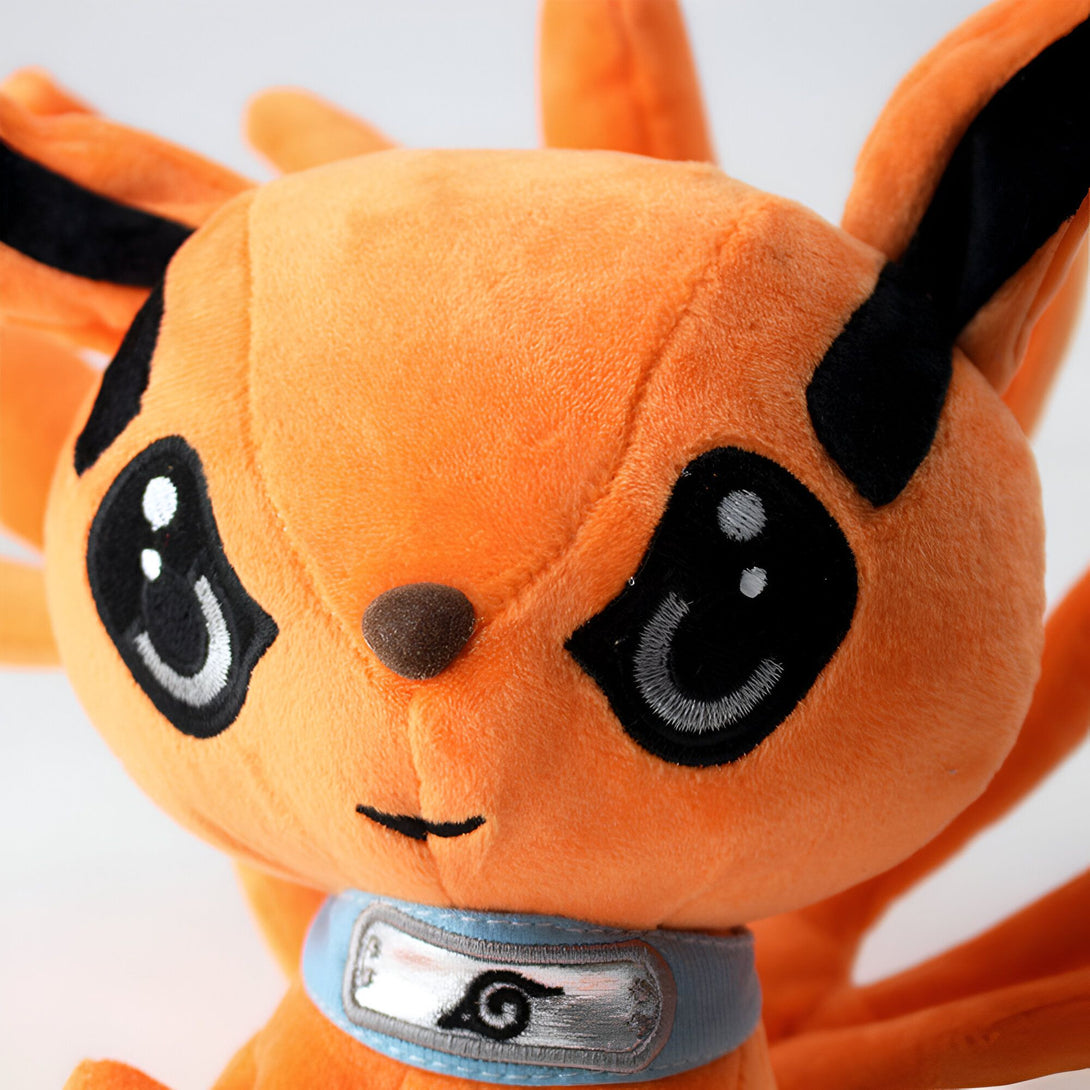 Peluche de Kurama, le renard à neuf queues de Naruto, avec un collier bleu portant l'emblème de Konoha.