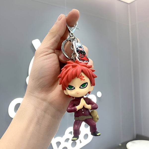Porte-clés Naruto représentant le personnage de Gaara, portant sa tenue rouge et tenant ses mains jointes.  Il est accompagné d'un charm représentant le personnage de Gaara.  Ce porte-clés est un accessoire idéal pour les fans de Naruto.