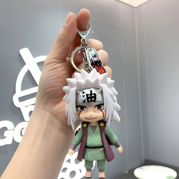 Porte-clés Naruto avec une figurine de Jiraya en tenue verte et rouge. Il porte un bandeau avec l'idéogramme "huile" et un petit porte-clés représentant Naruto.