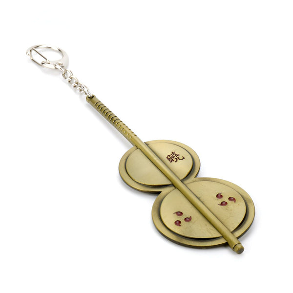 Porte-clés en métal doré représentant le symbole du Sharingan de Sasuke avec les kanji "Sasuke" inscrits sur l'un des disques.