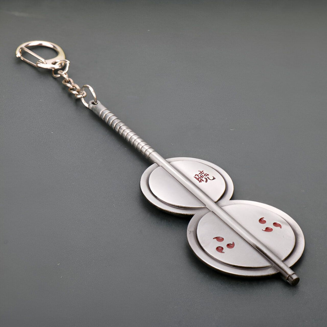 Porte-clés en métal représentant le symbole du clan Uchiwa, avec l'inscription "Sharingan" en kanji.