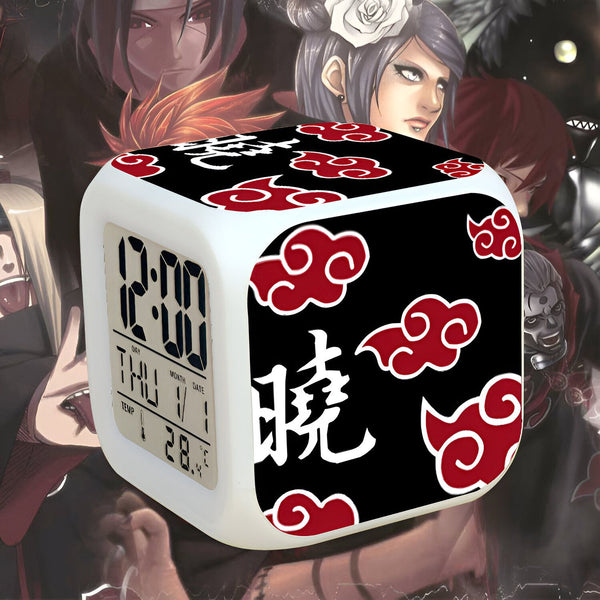 Horloge numérique blanche avec un motif noir et rouge représentant le symbole du Sharingan de Naruto et le kanji pour "Sharingan". Elle affiche l'heure, le jour, le mois et la température.