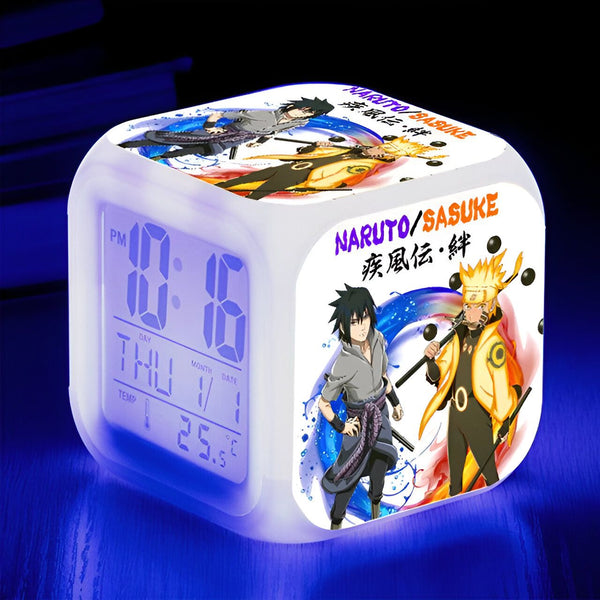 Horloge numérique blanche avec des personnages de l'anime Naruto et Sasuke. L'horloge affiche l'heure, le jour, le mois et la température.  L'horloge est éclairée d'une lumière bleue.