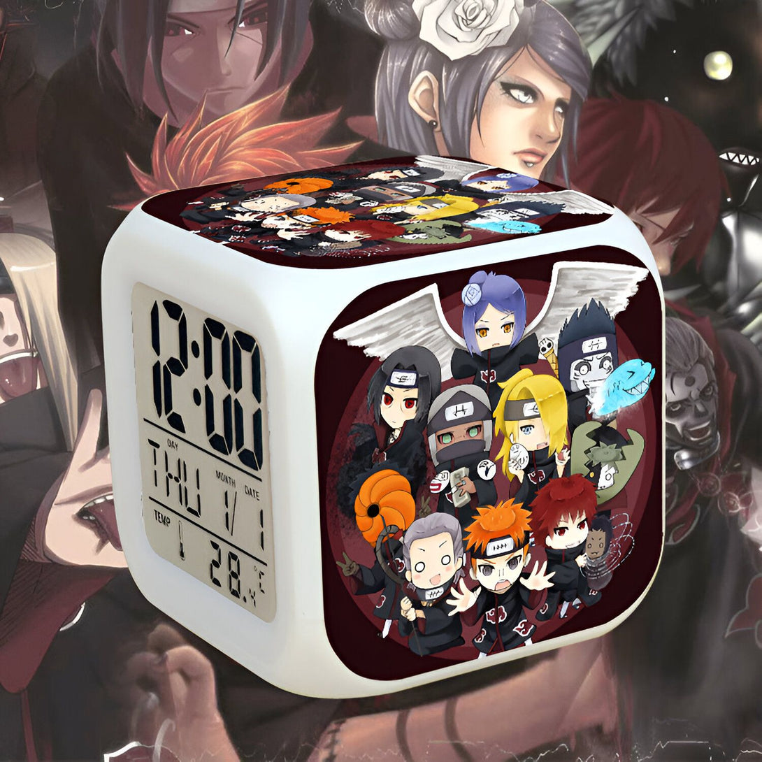 Horloge numérique blanche avec un design Naruto. L'horloge affiche l'heure, le jour et la température. Le design présente des personnages populaires de Naruto, tels que Kakashi, Sasuke, Itachi, Sakura et Naruto. Un excellent cadeau pour les fans de Naruto.