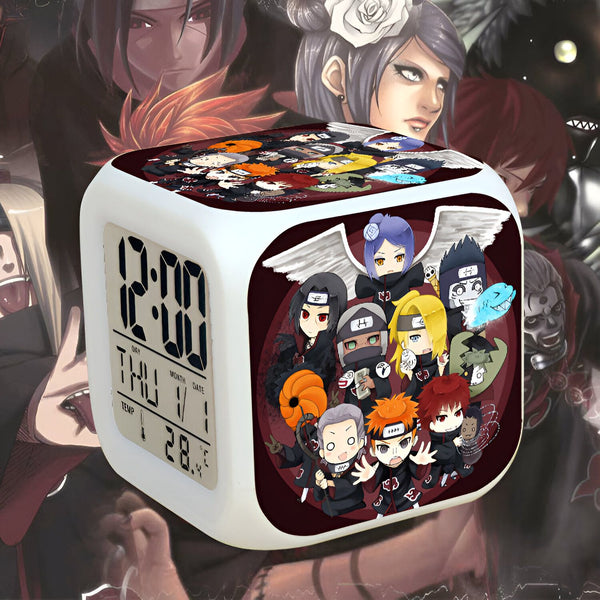 Horloge numérique blanche avec un design Naruto. L'horloge affiche l'heure, le jour et la température. Le design présente des personnages populaires de Naruto, tels que Kakashi, Sasuke, Itachi, Sakura et Naruto. Un excellent cadeau pour les fans de Naruto.