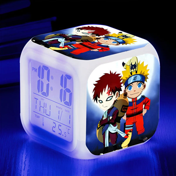 Horloge numérique blanche avec l'image d'un personnage de Naruto, sur fond bleu. On peut voir des personnages comme Kakashi, Gaara et Naruto sur l'horloge.
