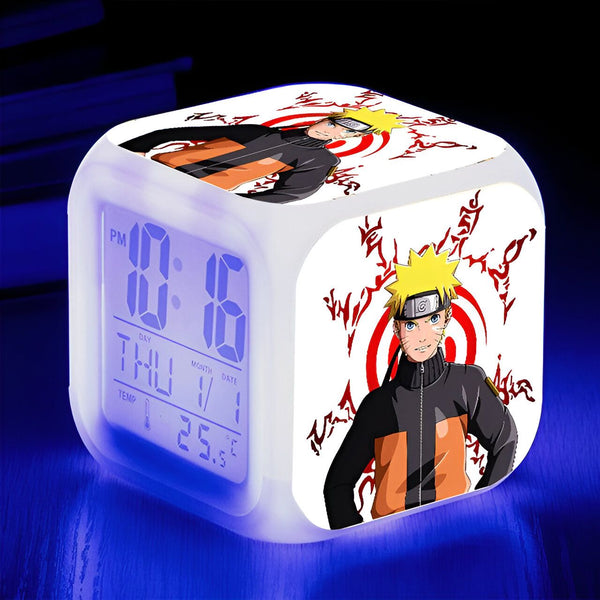 Horloge numérique blanche avec l'image de Naruto Uzumaki, un personnage de l'anime Naruto, portant son costume orange signature. Il est debout devant le symbole de son clan. L'horloge est également équipée d'un affichage de l'heure, du jour, de la date et de la température.