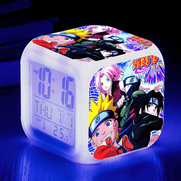 Réveil numérique blanc avec un design Naruto. L'horloge affiche l'heure, le jour et la température. Le réveil est décoré avec des personnages de Naruto comme Naruto Uzumaki, Sasuke Uchiha, Sakura Haruno et Kakashi Hatake.