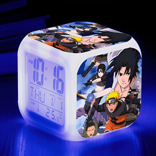 Réveil numérique avec un design Naruto. L'horloge affiche l'heure, le jour et la température. L'image présente des personnages populaires de l'anime, dont Naruto, Sasuke et Kakashi. Un excellent ajout à tout collectionneur de Naruto.