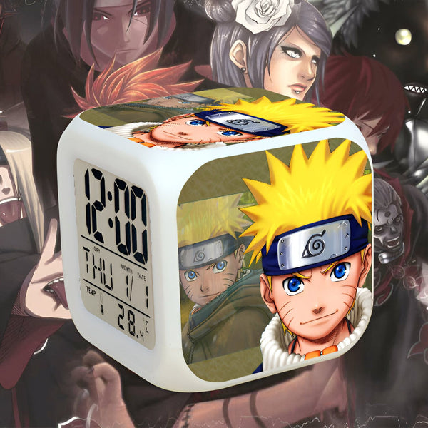Réveil numérique avec l'image de Naruto Uzumaki et d'autres personnages de l'anime Naruto. Le réveil est blanc et a un design cubique. Il affiche l'heure, le jour et la température.