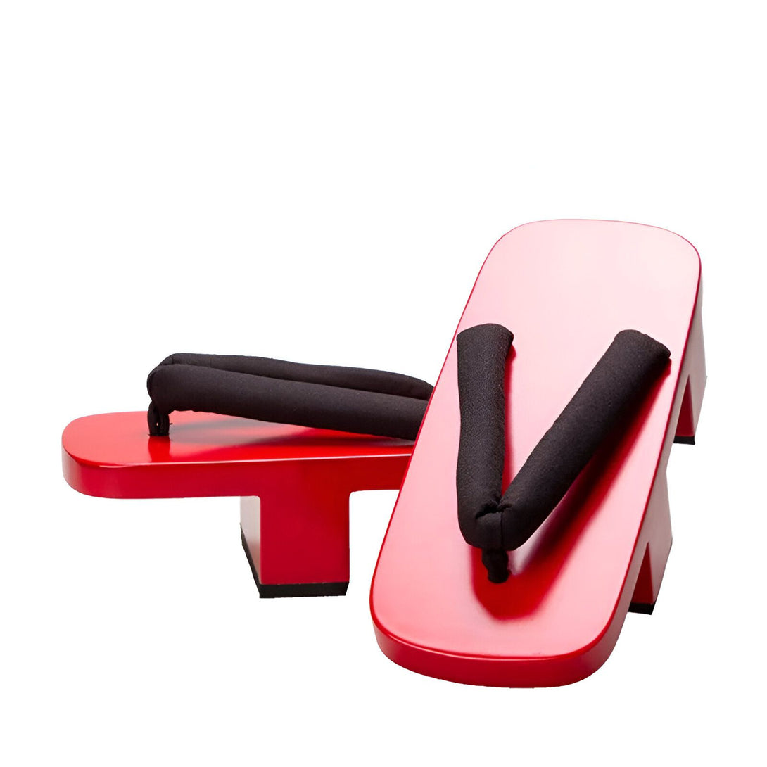 Une paire de sandales japonaises rouges en bois, appelées geta, avec des lanières noires. Ces sandales sont traditionnelles et élégantes.