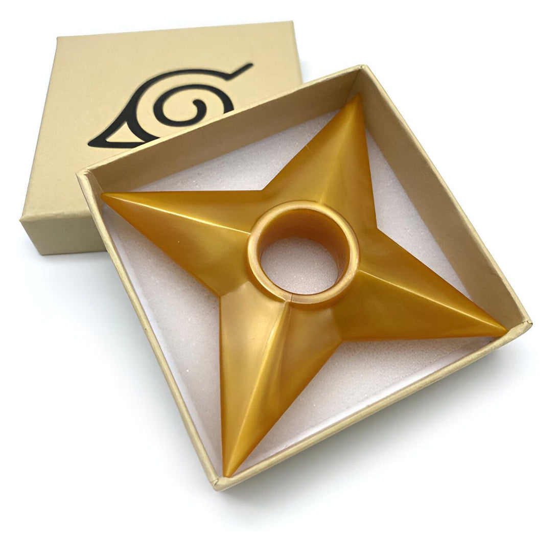 Un shuriken doré à cinq pointes dans un coffret en carton avec le logo de Konoha.