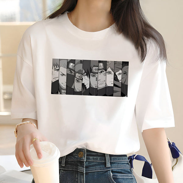 Une femme portant un t-shirt blanc avec un imprimé en noir et blanc des personnages de l'anime Naruto.  Le t-shirt est un produit de la marque Naruto.