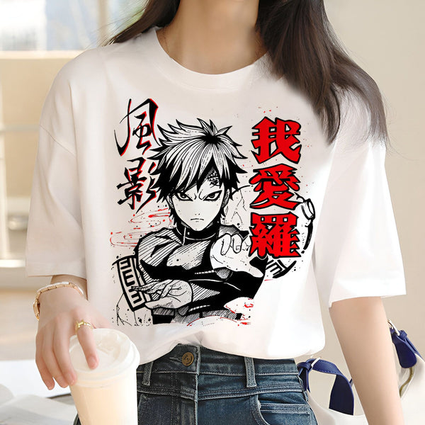 Une femme porte un t-shirt blanc avec un imprimé de Naruto Uzumaki, un personnage du manga et anime Naruto. Le design présente Naruto en noir et blanc, avec des accents rouges, dans une pose de combat. L'impression inclut également des caractères japonais.