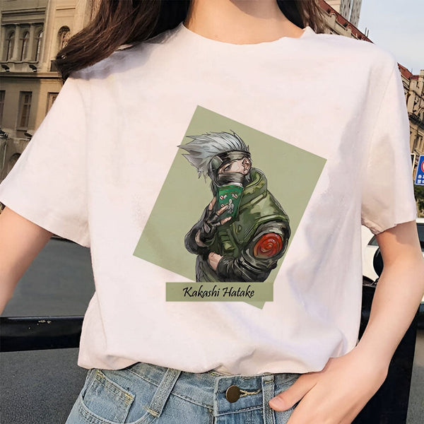 Un t-shirt blanc avec un imprimé de Kakashi Hatake, un personnage de l'anime Naruto, portant un bandeau et tenant un livre. Le t-shirt est porté par une femme avec des jeans.