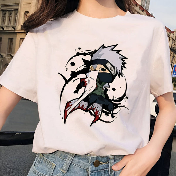T-shirt blanc avec un design d'anime de Kakashi Hatake de la série Naruto. Kakashi est représenté dans un style chibi, avec des yeux noirs et un bandeau rouge sur le front. Il porte son costume de ninja signature et est en position d'attaque.