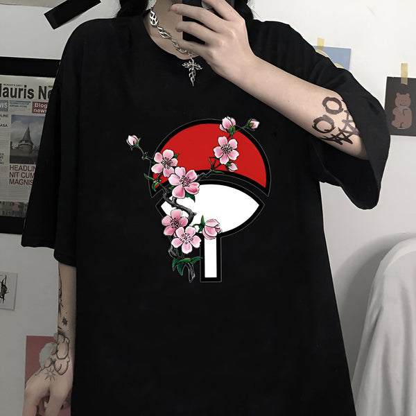 T-shirt noir avec un motif d'un symbole rouge et blanc de l'anime Naruto entouré de fleurs de cerisier roses.