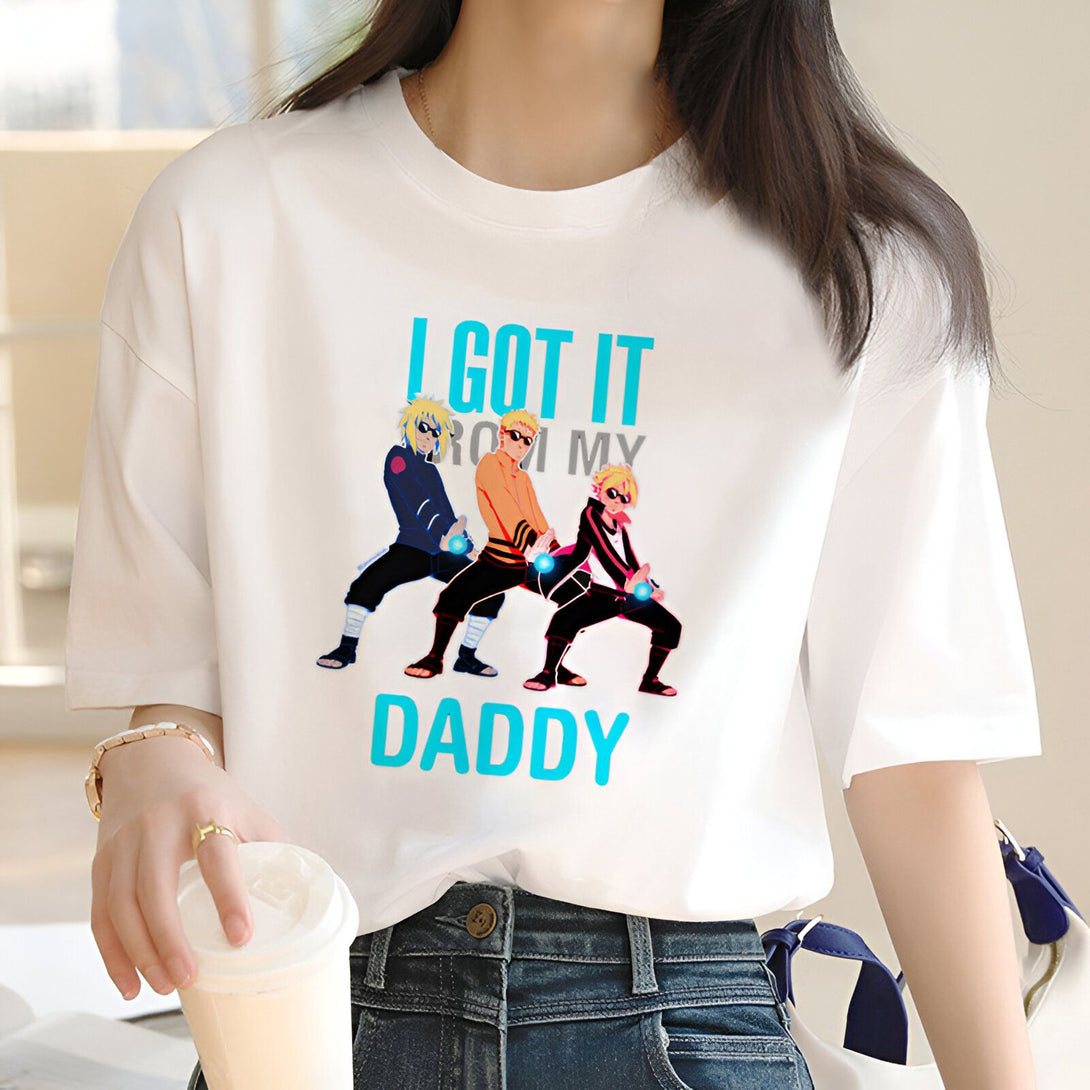 Une femme portant un t-shirt blanc avec l'impression "I got it from my daddy" et l'image des personnages de Naruto, Kakashi, Naruto et Sasuke, faisant la pose "Dab".  Le t-shirt est un produit de la marque Naruto.