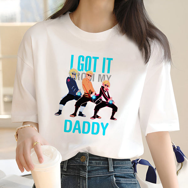 Une femme portant un t-shirt blanc avec l'impression "I got it from my daddy" et l'image des personnages de Naruto, Kakashi, Naruto et Sasuke, faisant la pose "Dab".  Le t-shirt est un produit de la marque Naruto.