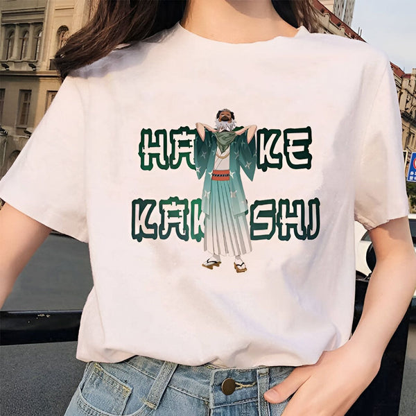 Un t-shirt blanc avec l'impression d'un personnage de manga, Kakashi Hatake, portant une tenue verte et blanche. Le t-shirt est écrit "HATAKE KAKASHI" en japonais.