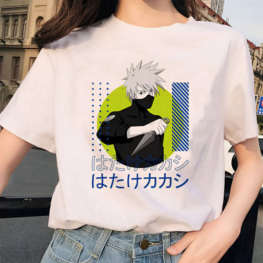 Un t-shirt blanc avec une image de Kakashi Hatake du manga Naruto. Il porte un masque et tient un kunai. Le t-shirt a un motif géométrique autour de Kakashi. Le texte "はたけカカシ" est écrit en japonais en dessous de l'image.