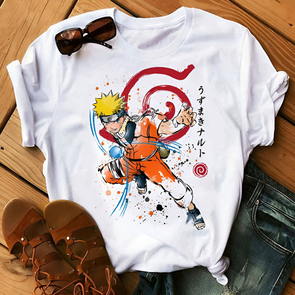 T-shirt blanc avec un imprimé de Naruto Uzumaki en action, portant sa tenue orange emblématique et effectuant le Rasengan. Le logo de Konoha est également présent, ainsi que des éclaboussures de peinture. Le t-shirt est posé sur un fond en bois et accompagné d'une paire de sandales.