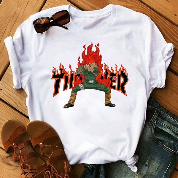 T-shirt blanc avec un imprimé de Jiraya du manga Naruto. Jiraya est entouré de flammes avec le mot "Thriier" écrit en noir en dessous. Le t-shirt est posé sur un fond en bois avec des jeans et des sandales.