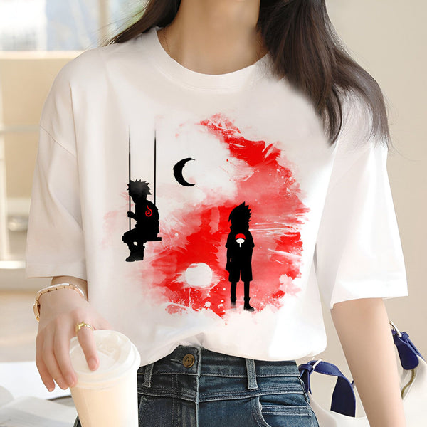 Une femme porte un t-shirt blanc avec un imprimé de Naruto et Sasuke. Naruto est sur une balançoire et Sasuke se tient debout. Le fond est rouge avec des éclaboussures de peinture et une lune.