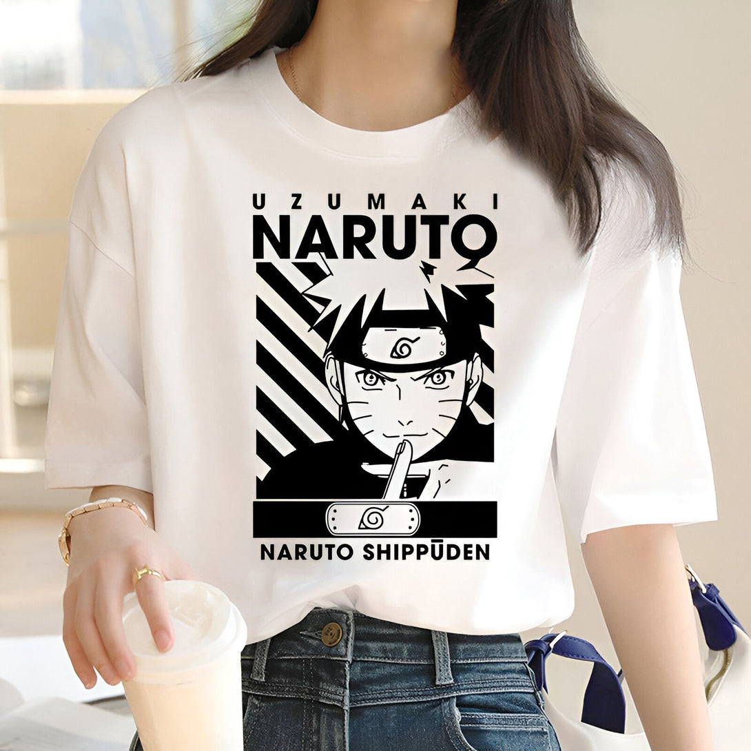 Une femme porte un t-shirt blanc avec un imprimé de Naruto Uzumaki, le personnage principal de l'anime Naruto. L'impression montre Naruto avec son célèbre bandeau frontal et son expression sérieuse. Le texte "Naruto Shippuden" est affiché en dessous du personnage.